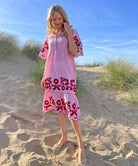 A model stood in sand dunes wearing a Rose and Rose red striped linen Agrigento dress.