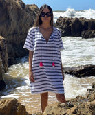 A model standing in front of the sea wearing a Rosebud by Rose and Rose Aix beach dress and sunglasses. 