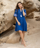 A model wears a Rose and Rose embroidered Ajaccio dress in french blue cotton.