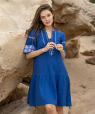 A model wears a Rose and Rose embroidered Ajaccio dress in french blue cotton.