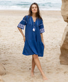 A model wears a Rose and Rose embroidered Ajaccio dress in french blue cotton.