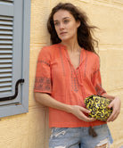 A model wears a Rose and Rose embroidered Antibes top in coral cotton.