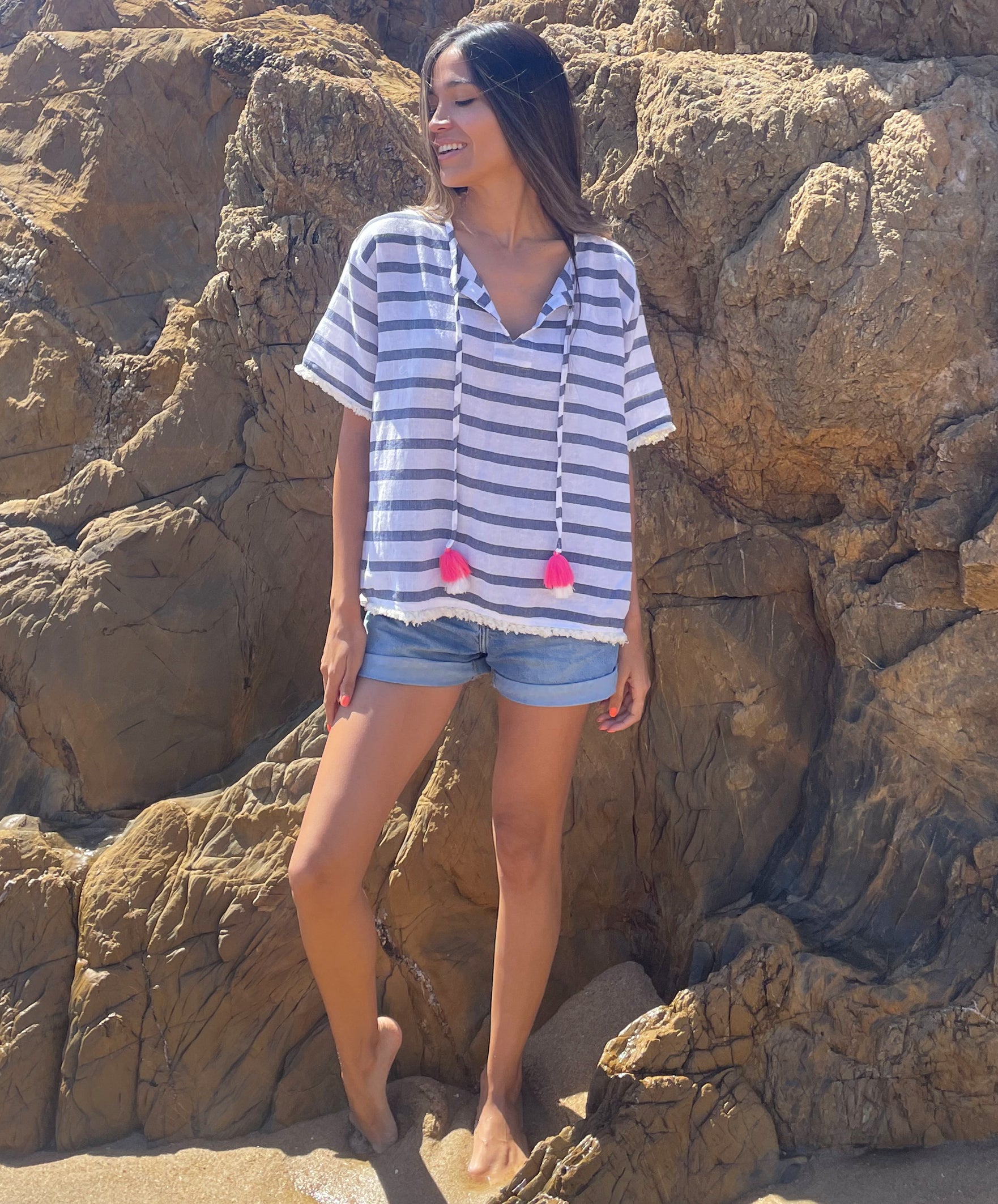A model stood on a beach wearing a Rosebud by Rose and Rose Antibes top and denim cut off shorts. 