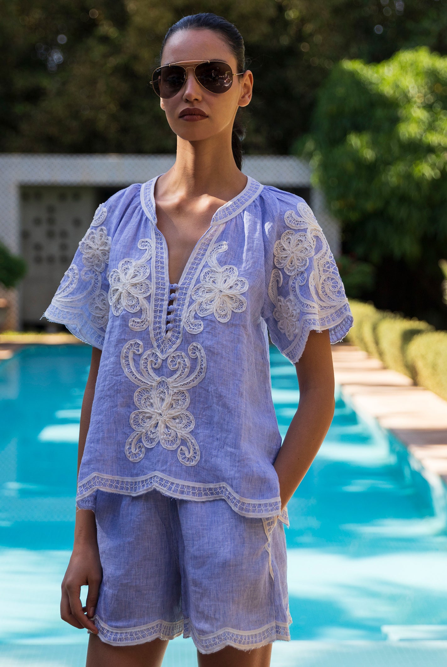 Woman wearing a blue striped Azalea blouse and matching short by a poolside
