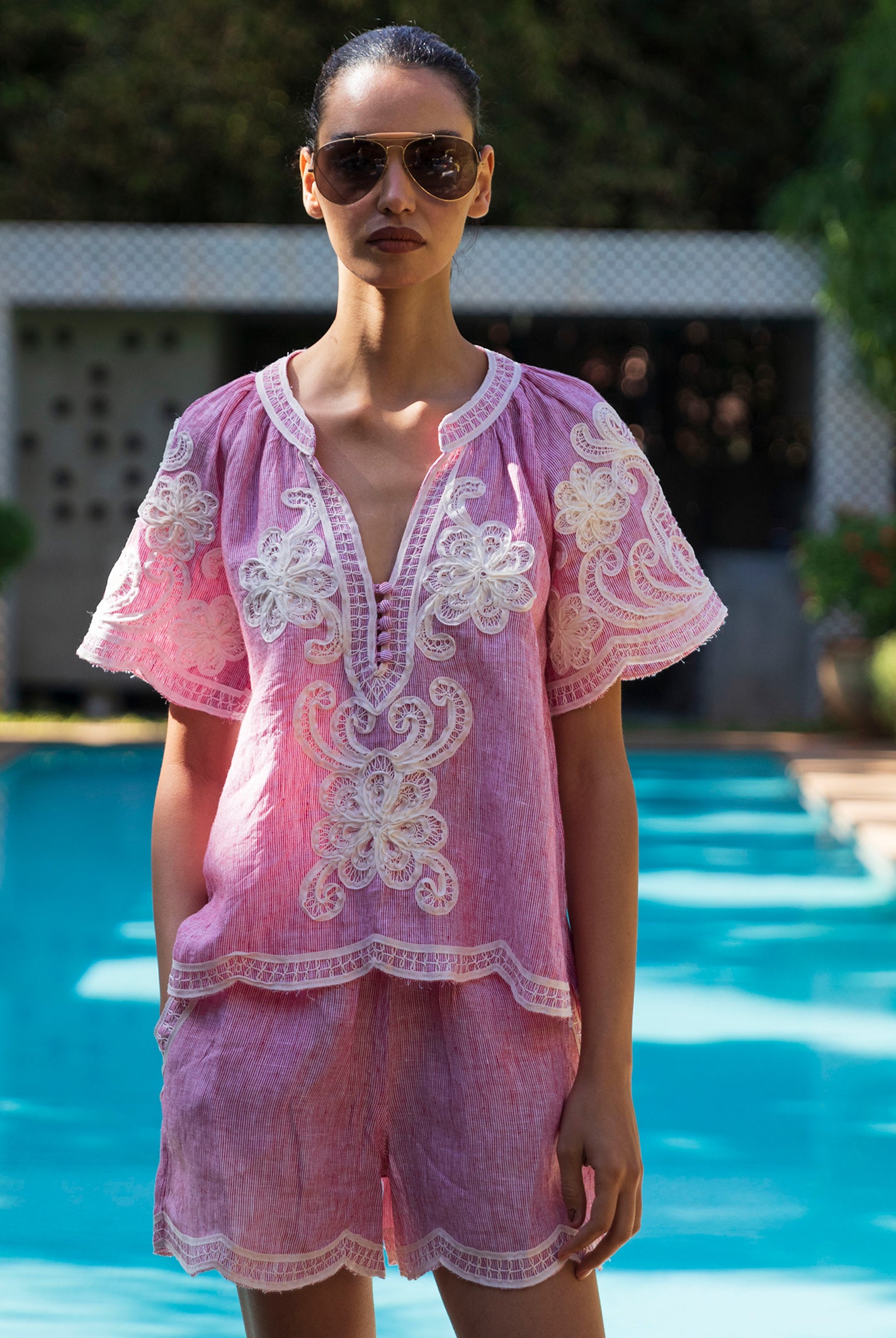 Woman wearing a red striped Azalea embroidered blouse with matching shorts by a pool