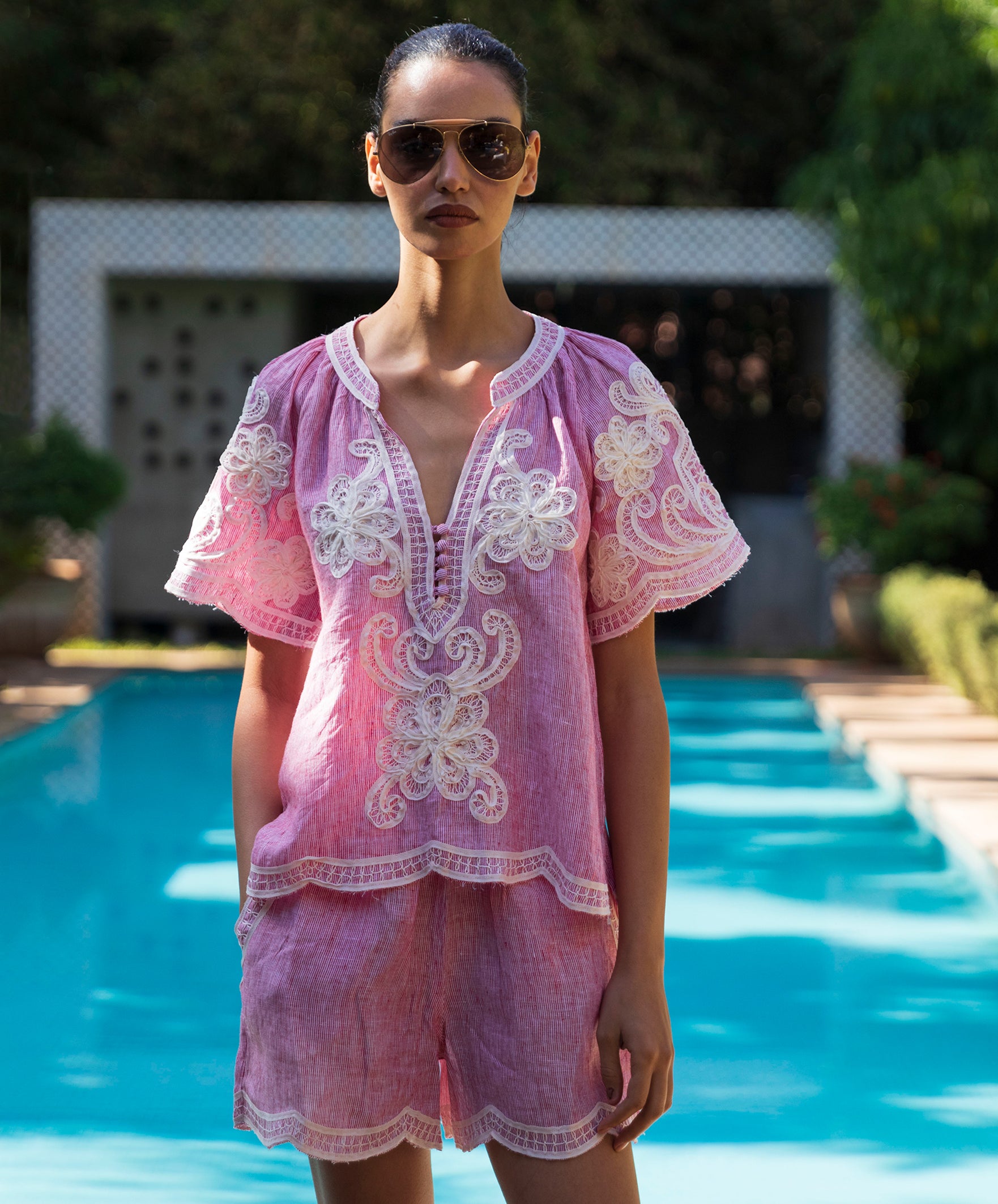 Woman wearing a red striped Azalea embroidered blouse with matching shorts by a pool
