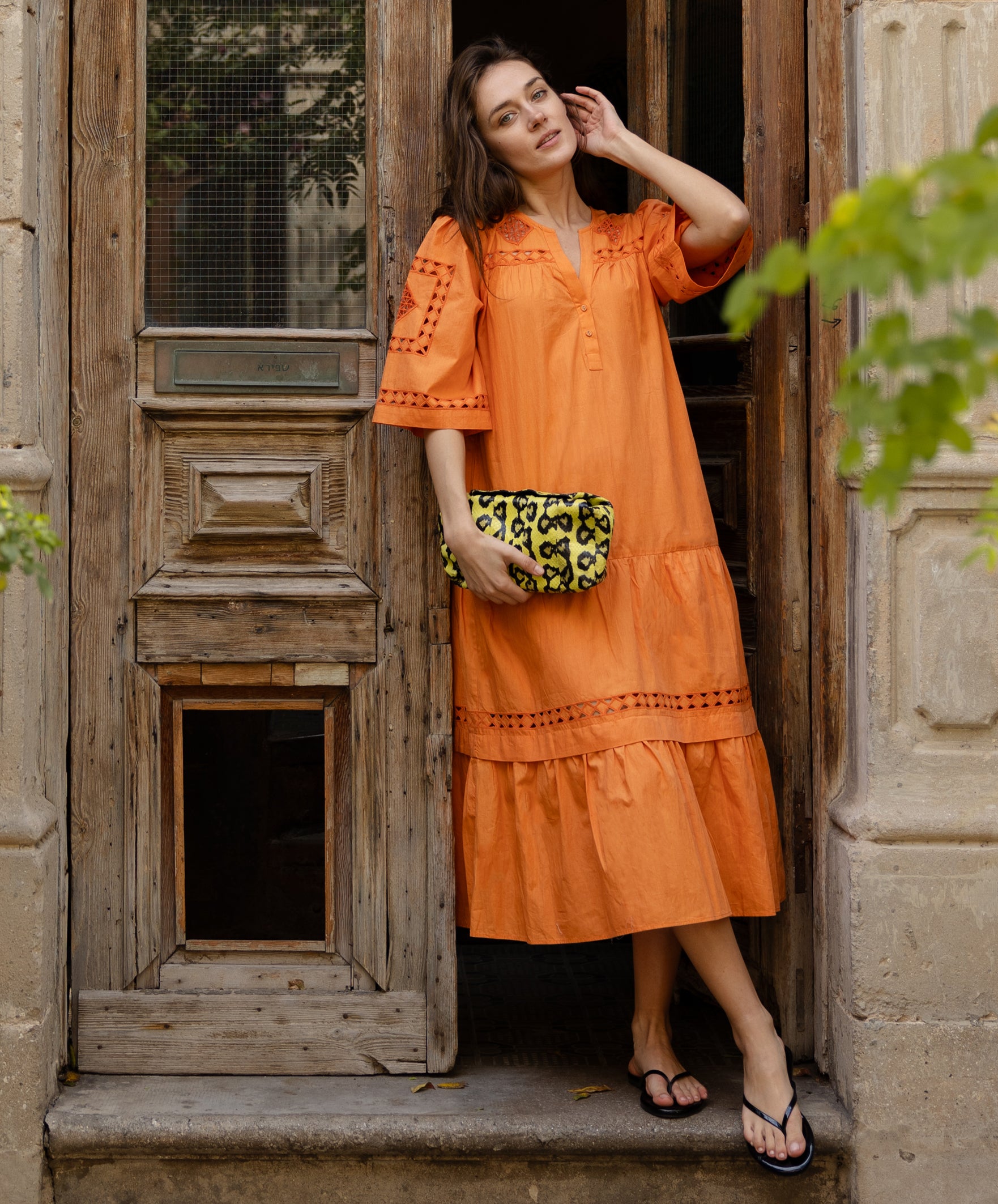 A model wears a Rose and Rose embroidered Biarritz dress in saffron orange cotton.