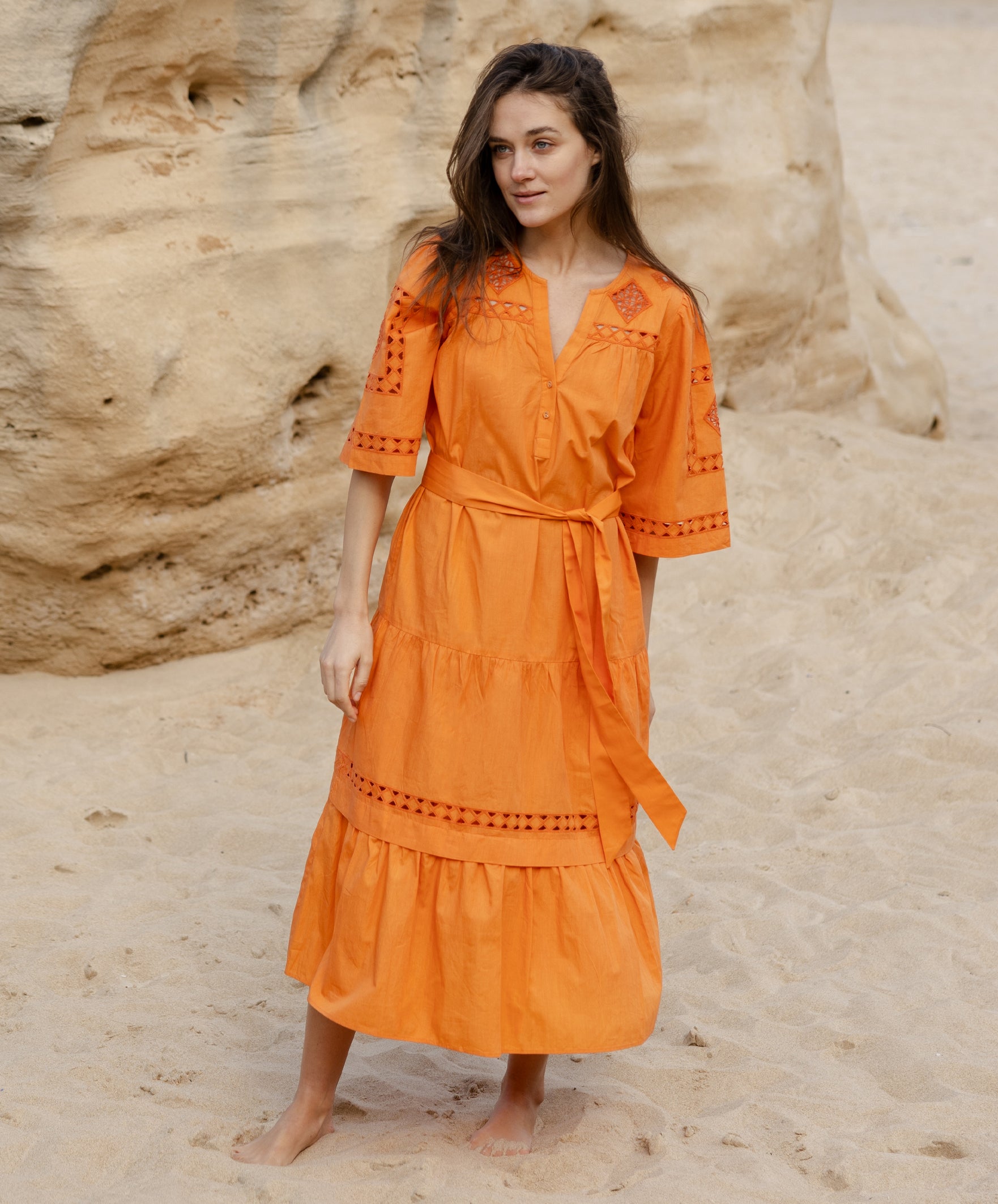 A model wears a Rose and Rose embroidered Biarritz dress in saffron orange cotton.