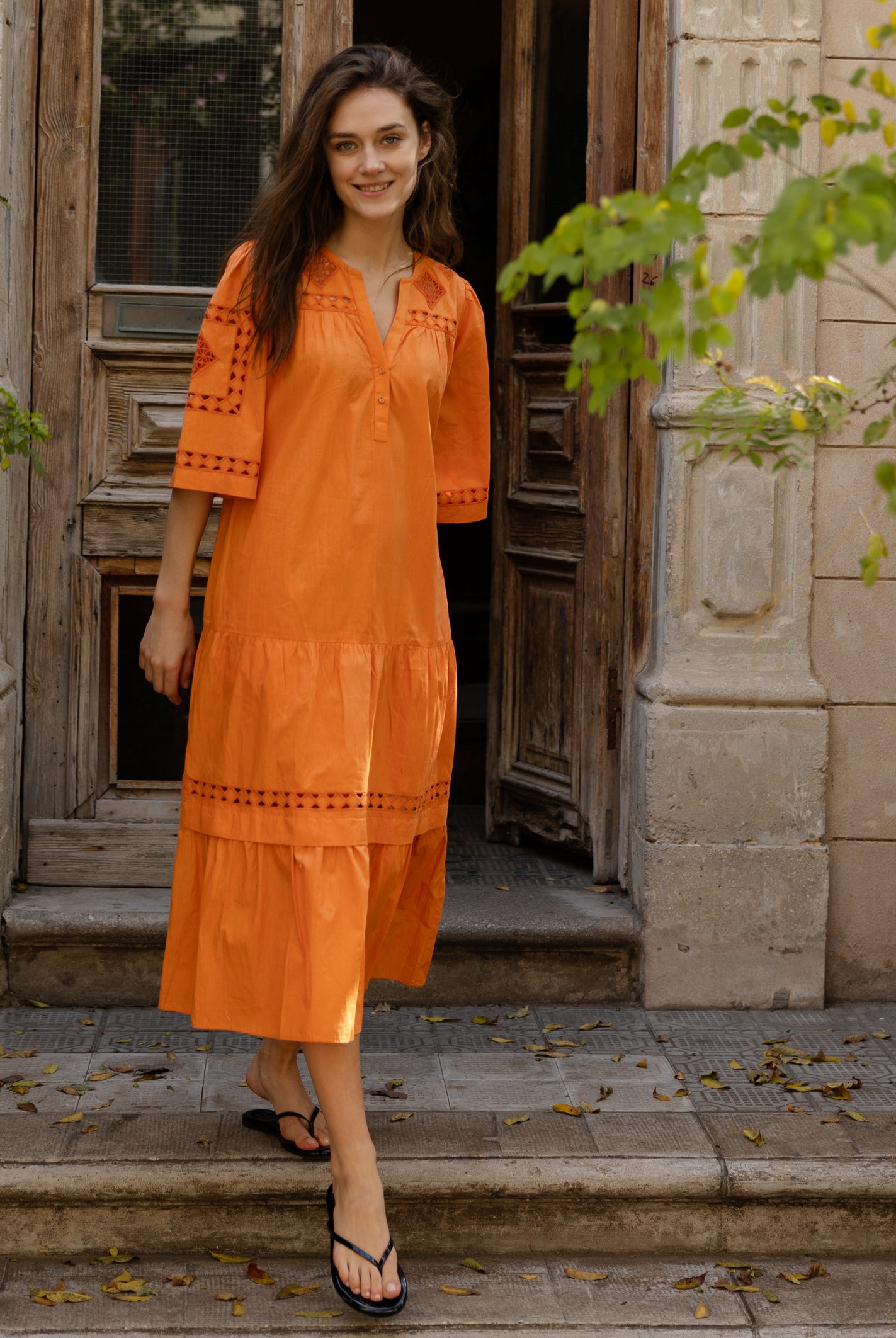 A model wears a Rose and Rose embroidered Biarritz dress in saffron orange cotton.