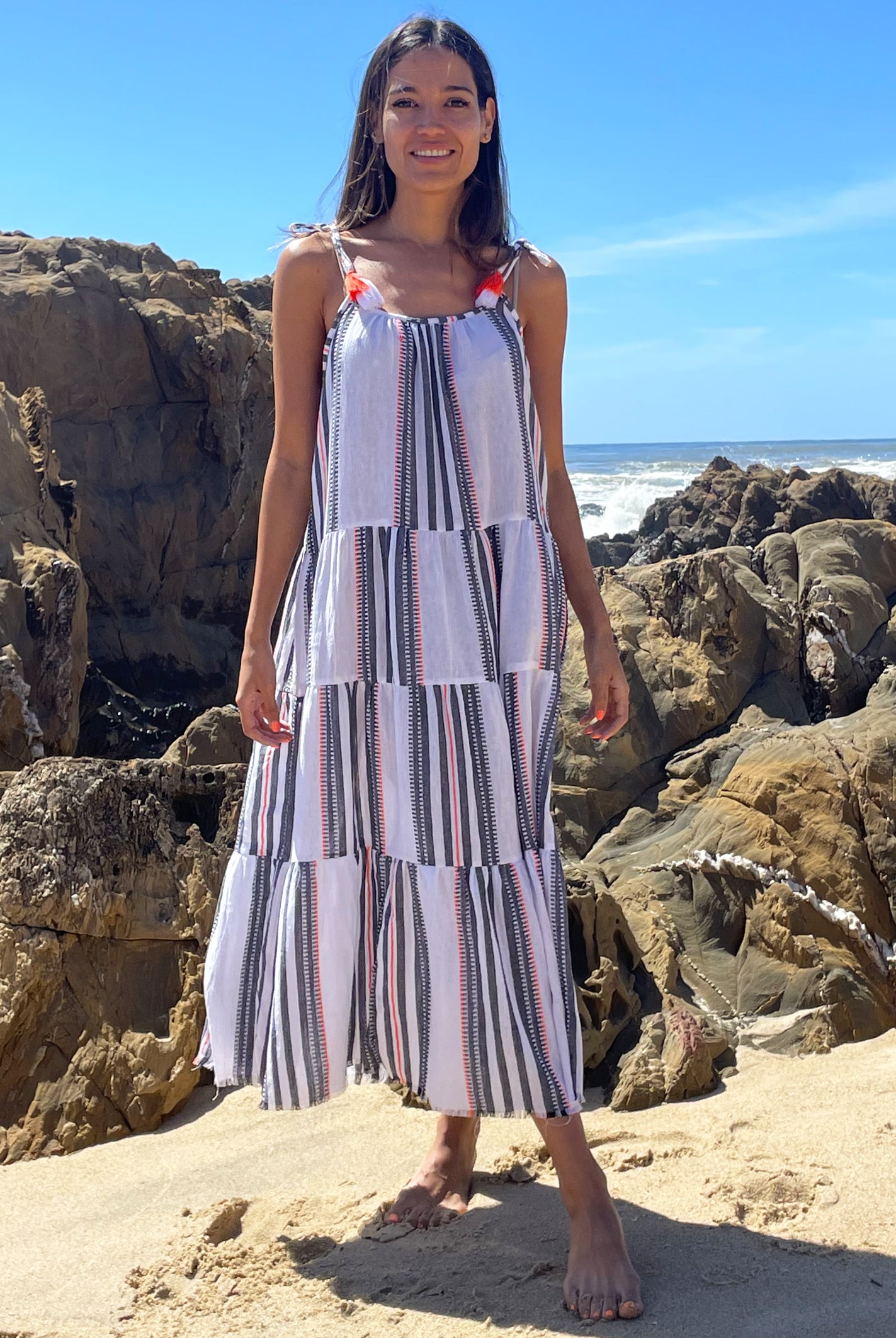 A model stood on a beach wearing a Rosebud by Rose and Rose Bias Dress.