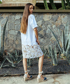 Back view of a model wearing a Rose and Rose Bond embroidered dress in white cotton.
