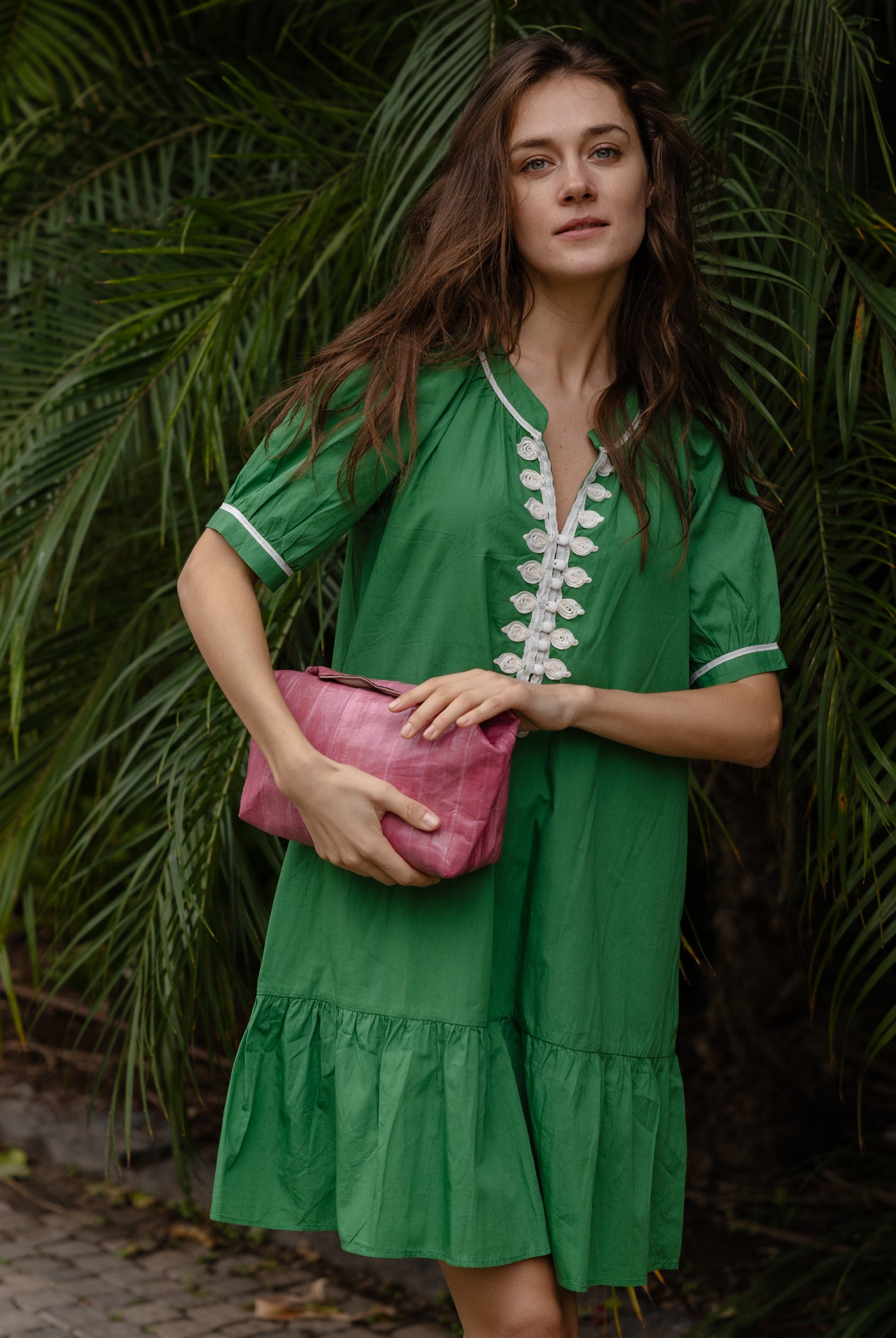 A model wearing a Rose and Rose green cotton Cannes dress with passementerie decoration.