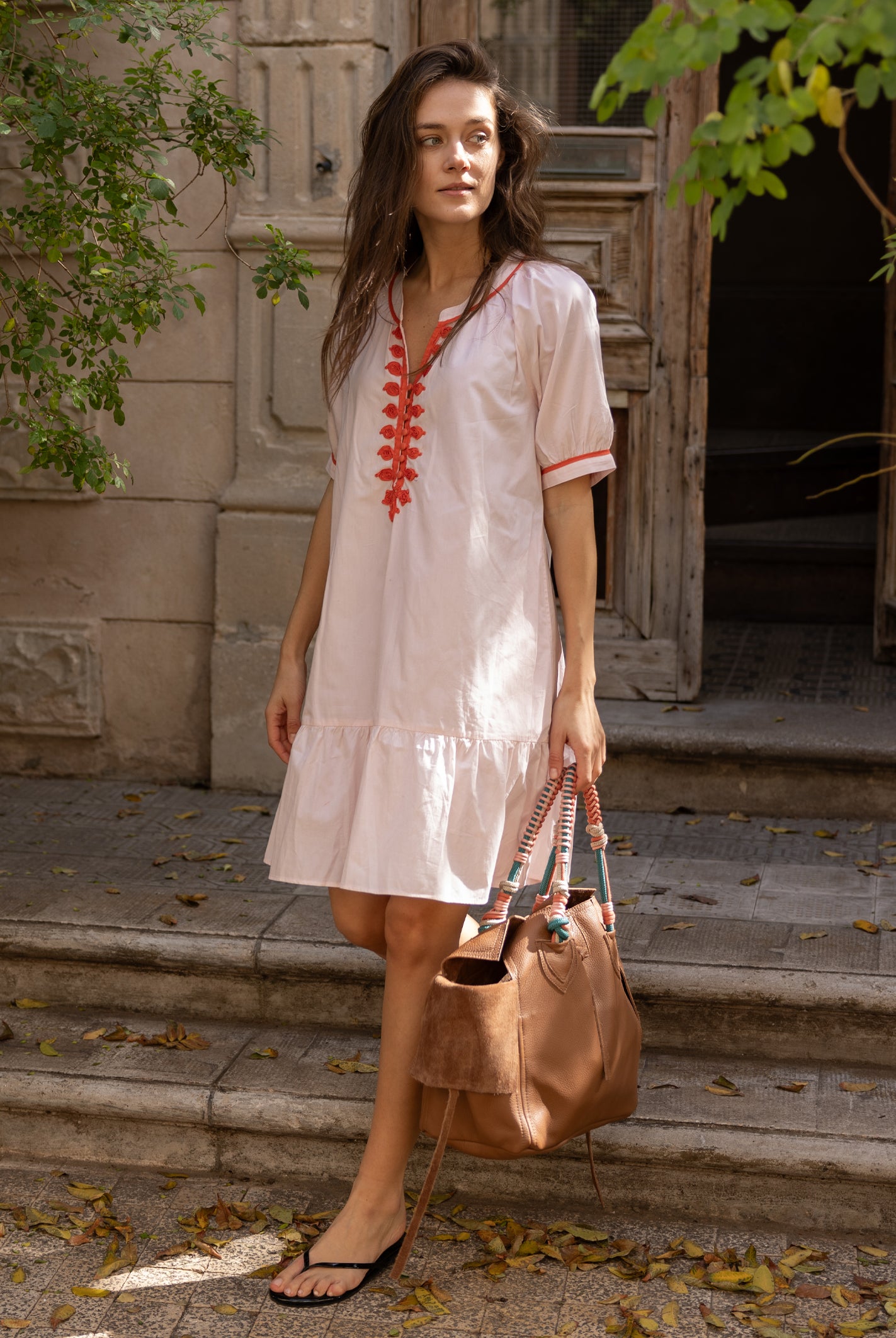 A model wearing a Rose and Rose pink cotton Cannes dress with passementerie decoration.