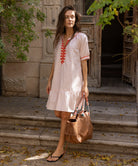 A model wearing a Rose and Rose pink cotton Cannes dress with passementerie decoration.