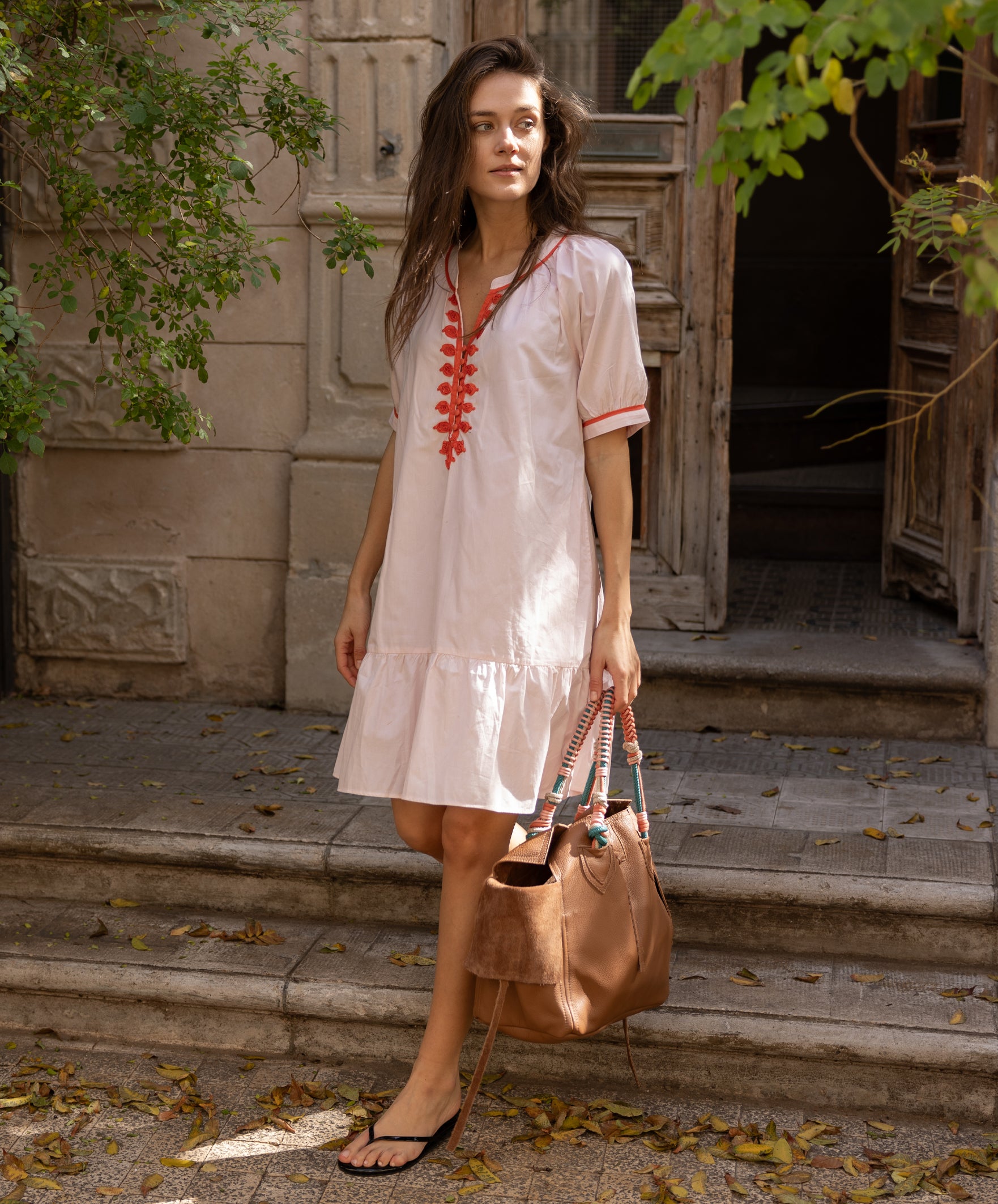 A model wearing a Rose and Rose pink cotton Cannes dress with passementerie decoration.