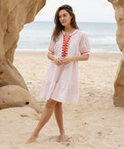 A model wearing a Rose and Rose pink cotton Cannes dress with passementerie decoration.
