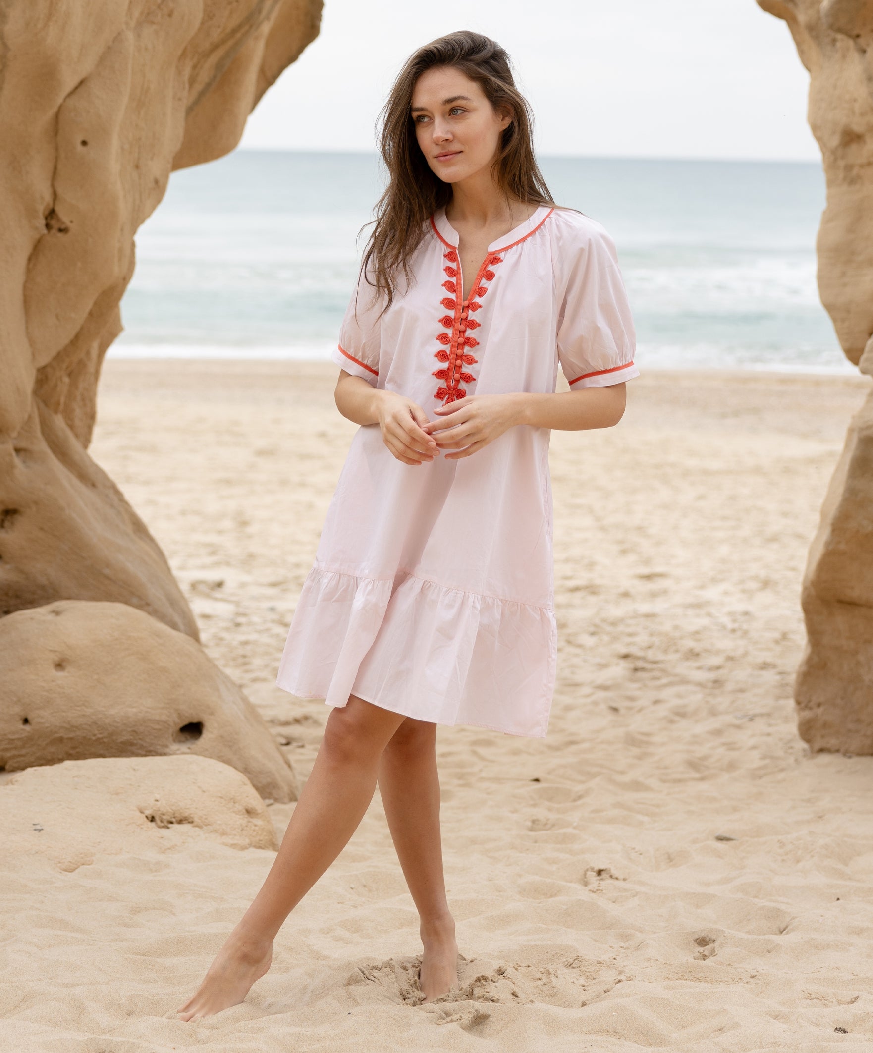 A model wearing a Rose and Rose pink cotton Cannes dress with passementerie decoration.