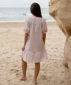 Back view of a model wearing a Rose and Rose pink cotton Cannes dress with passementerie decoration.