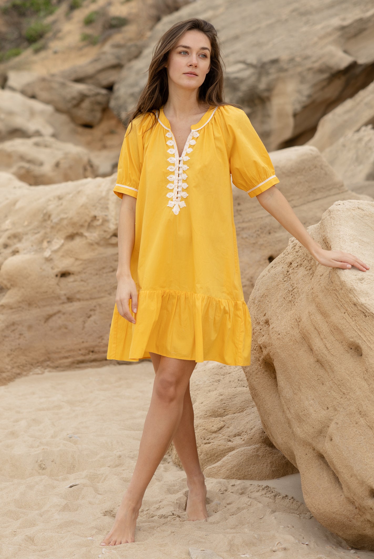 A model wearing a Rose and Rose yellow cotton Cannes dress with passementerie decoration.