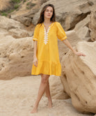A model wearing a Rose and Rose yellow cotton Cannes dress with passementerie decoration.