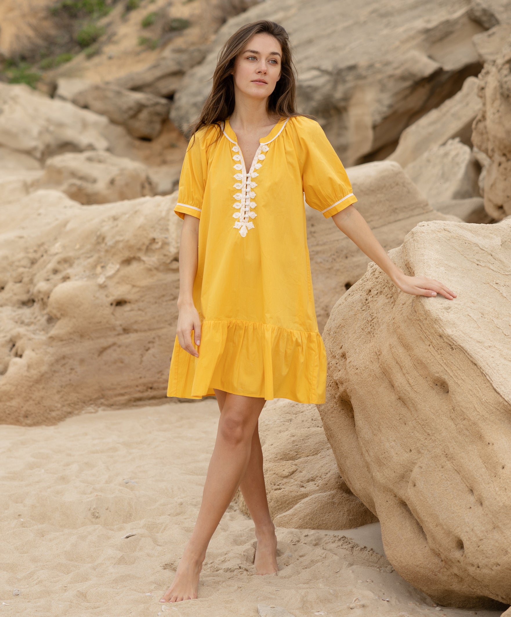 A model wearing a Rose and Rose yellow cotton Cannes dress with passementerie decoration.