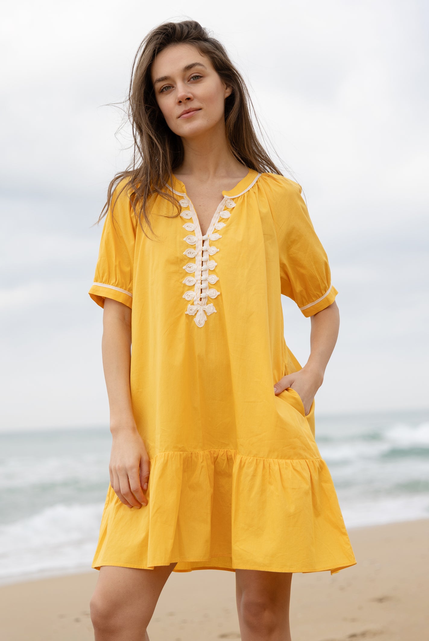 A model wearing a Rose and Rose yellow cotton Cannes dress with passementerie decoration.