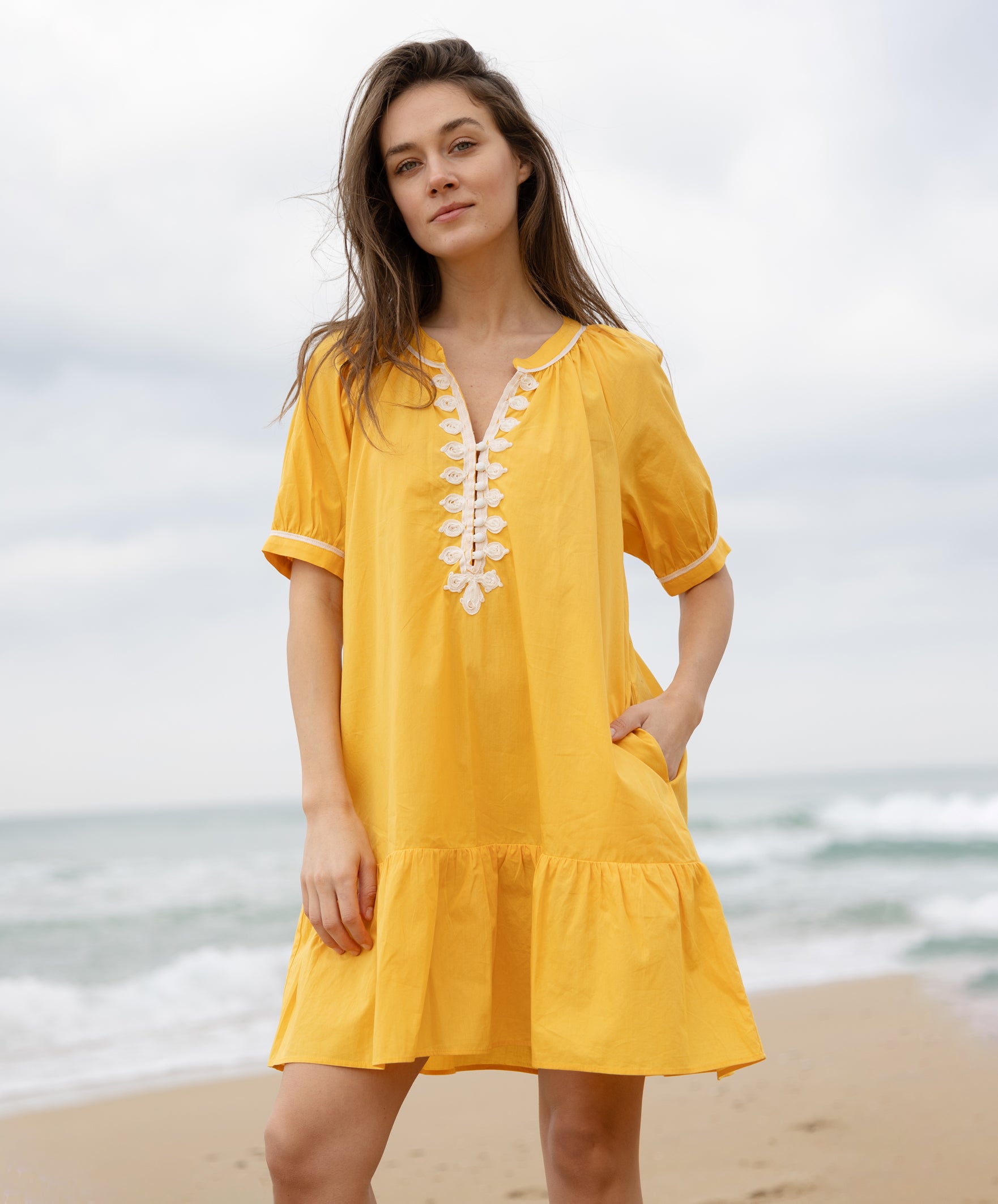 A model wearing a Rose and Rose yellow cotton Cannes dress with passementerie decoration.