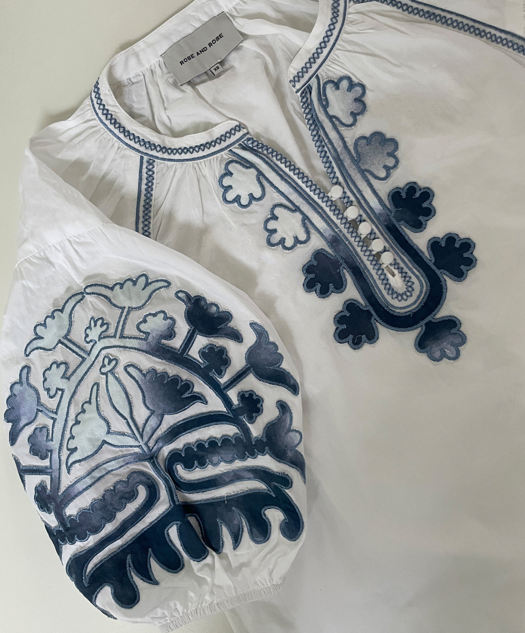 White blouse with blue embroidery on a light background