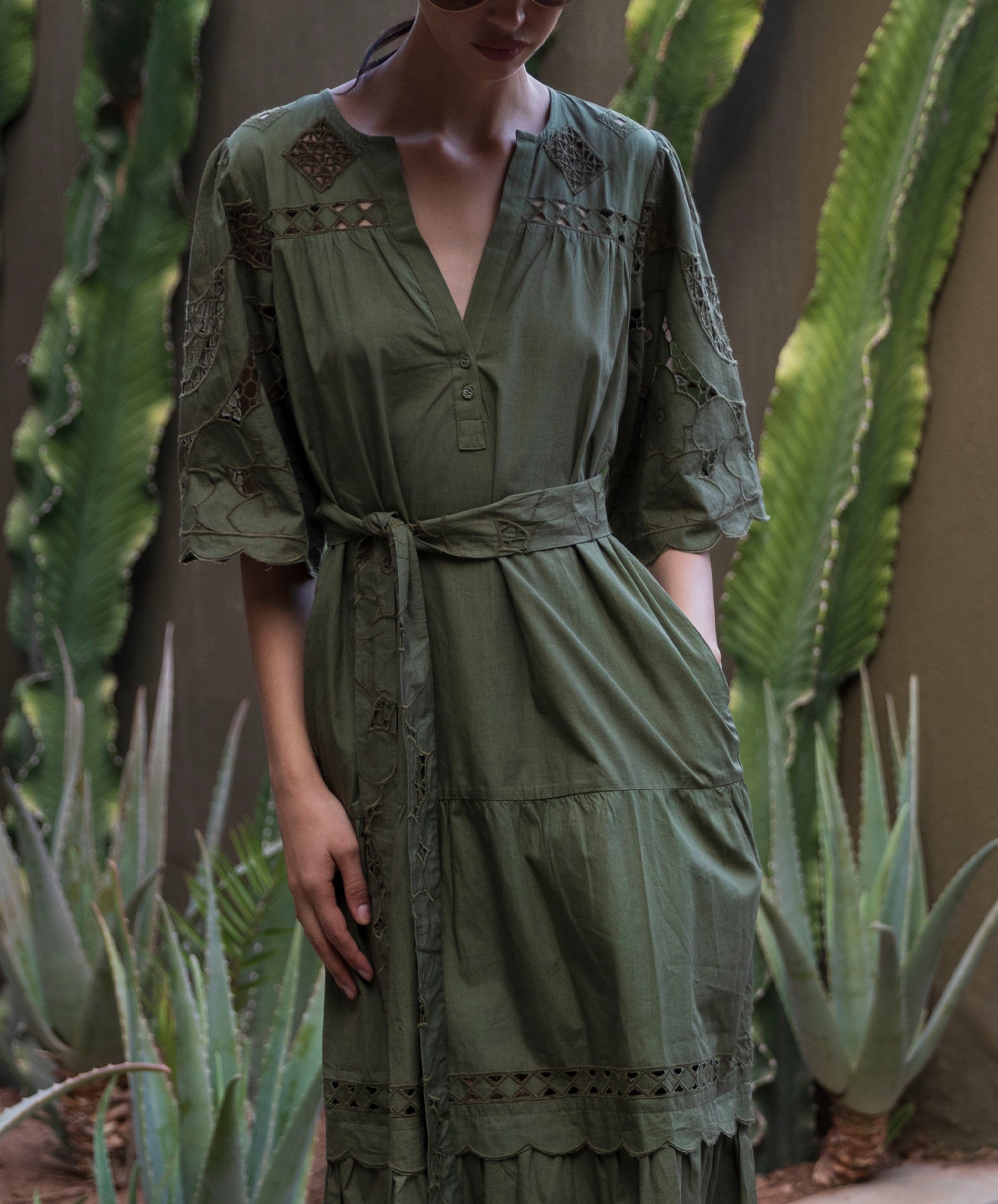 Woman wearing a green embroidered dress standing among cacti