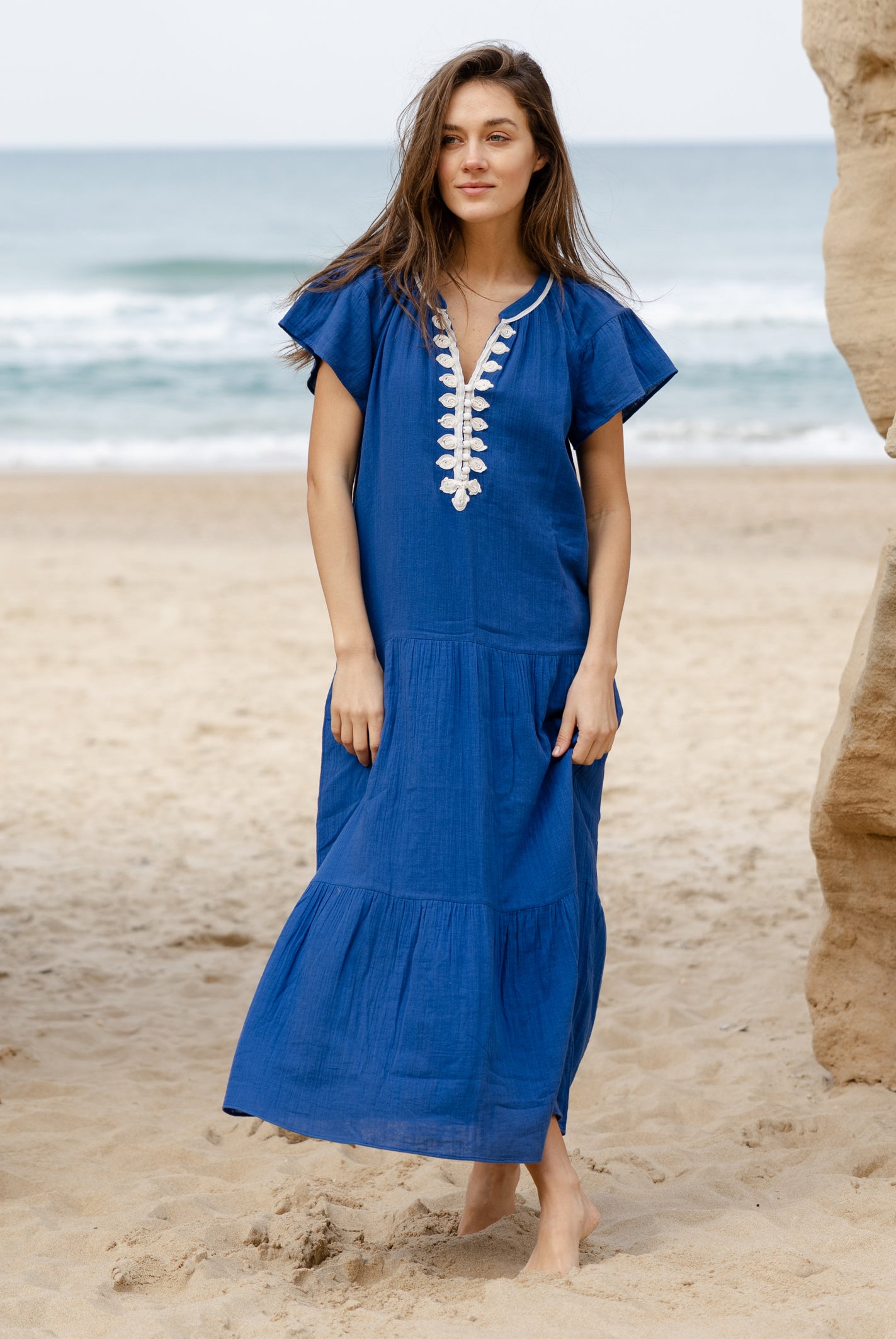 A model wearing a Rose and Rose Deauville blue maxi dress with passementerie decoration.