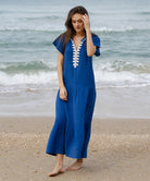 A model wearing a Rose and Rose Deauville blue maxi dress with passementerie decoration.