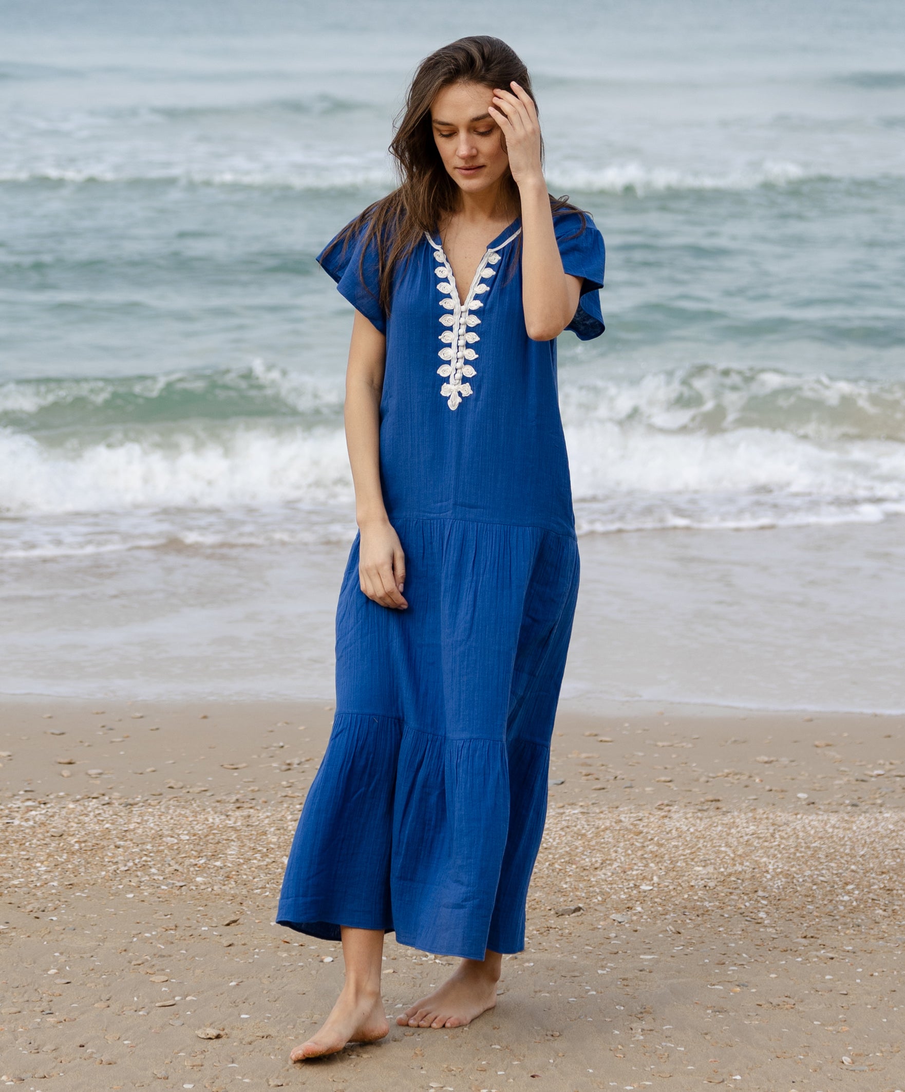 A model wearing a Rose and Rose Deauville blue maxi dress with passementerie decoration.