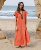 A model wearing a Rose and Rose Deauville coral maxi dress with passementerie decoration.