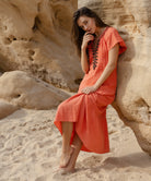 A model wearing a Rose and Rose Deauville coral maxi dress with passementerie decoration.