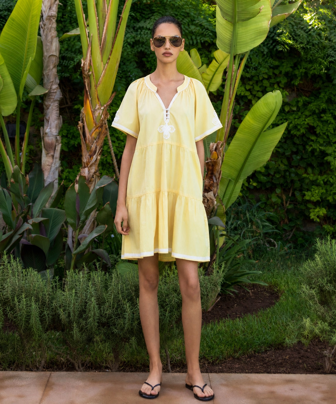 Woman in a yellow dress standing in a garden setting