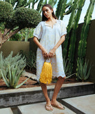 A model stood in a cacti garden wearing a cream Rose and Rose Gloucester cotton dress with gold lurex appliqué decoration.