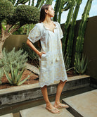 A model stood in a cacti garden wearing a cream Rose and Rose Gloucester cotton dress with gold lurex appliqué decoration.