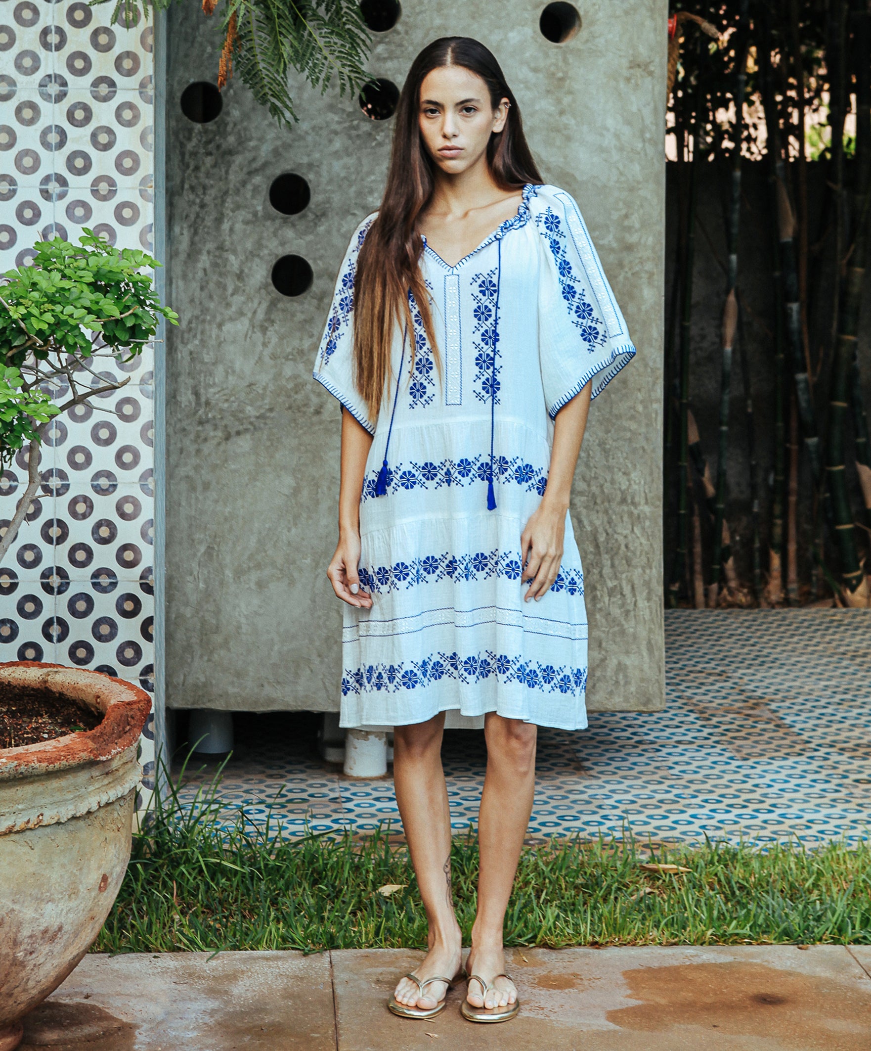 A model wearing a Rose and Rose Holborn  cotton dress in white with cobalt blue embroidery.
