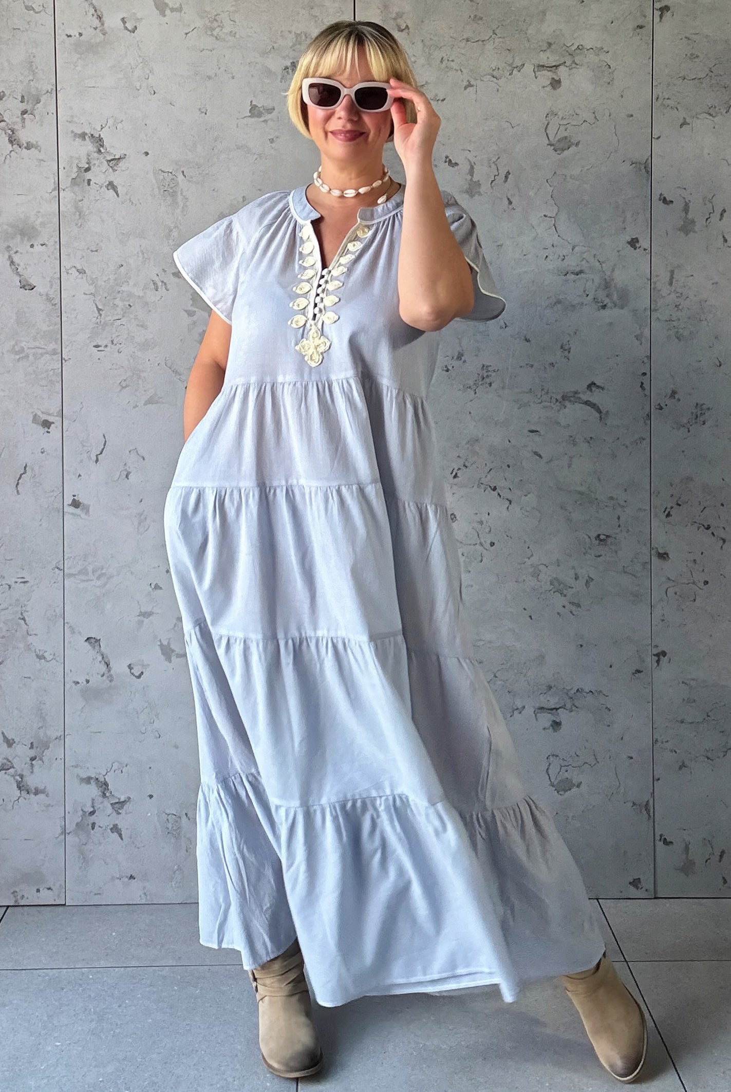 Woman wearing a blue striped dress against a gray concrete wall.