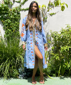 A model stood in a garden wearing Rose and Rose blue embroidered Livorno dress.