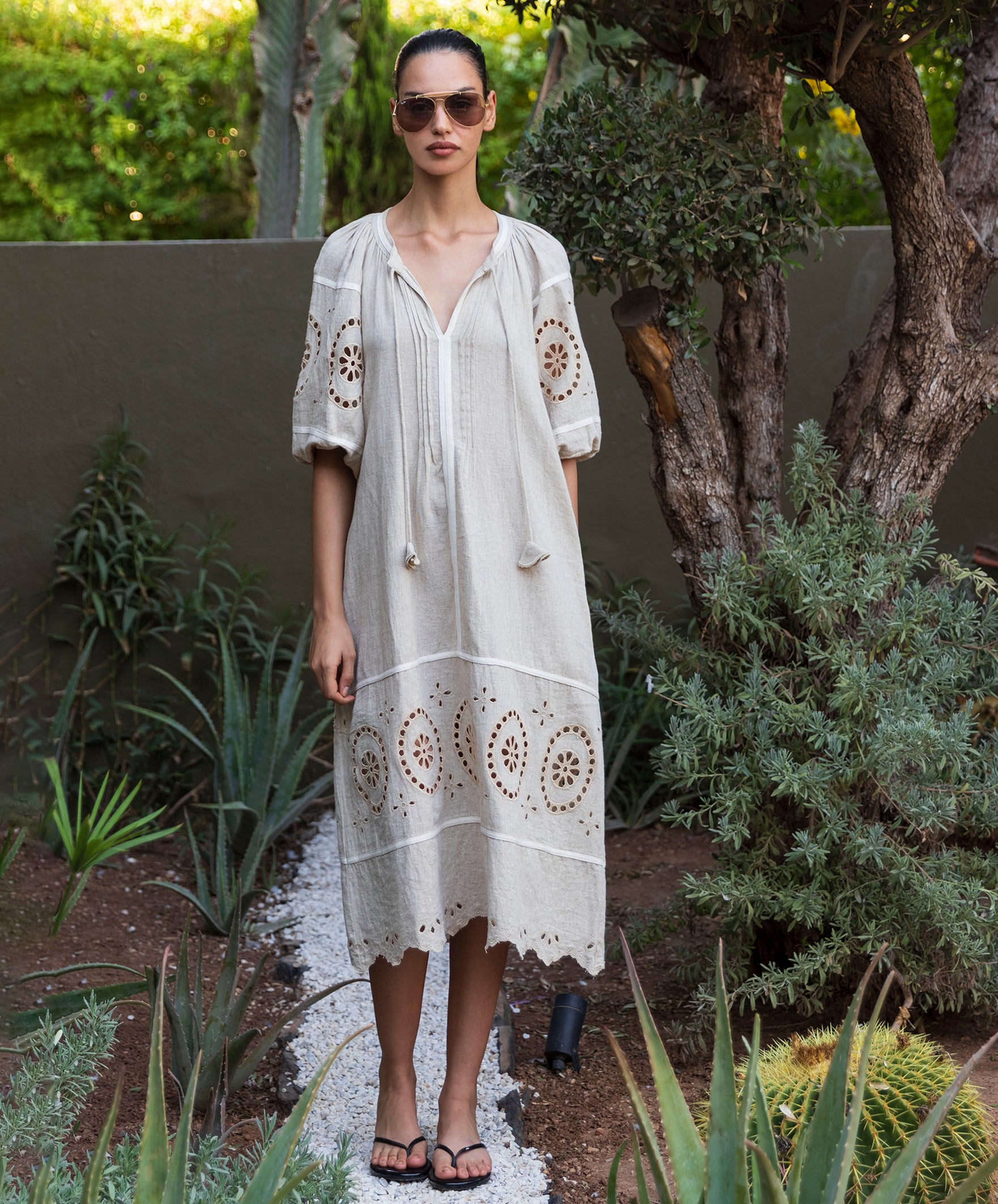 Woman in a natural linen dress with embroidery standing in a garden setting