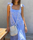 Close up of the embroidery on the Rose and Rose blue cotton Marina sundress and a white leather Dragon bag.