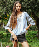 A model wearing a Rose and Rose Newbury white cotton top with olive embroidery.