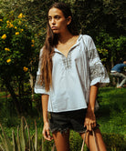 A model wearing a Rose and Rose Newbury white cotton top with olive embroidery.