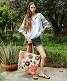 A model is wearing a Rose and Rose Newbury white cotton top with olive embroidery and carrying a Foodfoundation bag.
