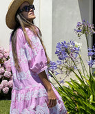 A model stood in a garden wearing a cowboy hat, sunglasses and a Rose and Rose pale pink Palermo embroidered dress.