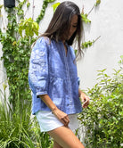  Side view of a model wearing the blue chambray linen Rose and Rose Sardinia top and white shorts.
