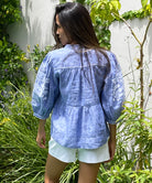 Back view of a model wearing the blue chambray linen Rose and Rose Sardinia top and white shorts.