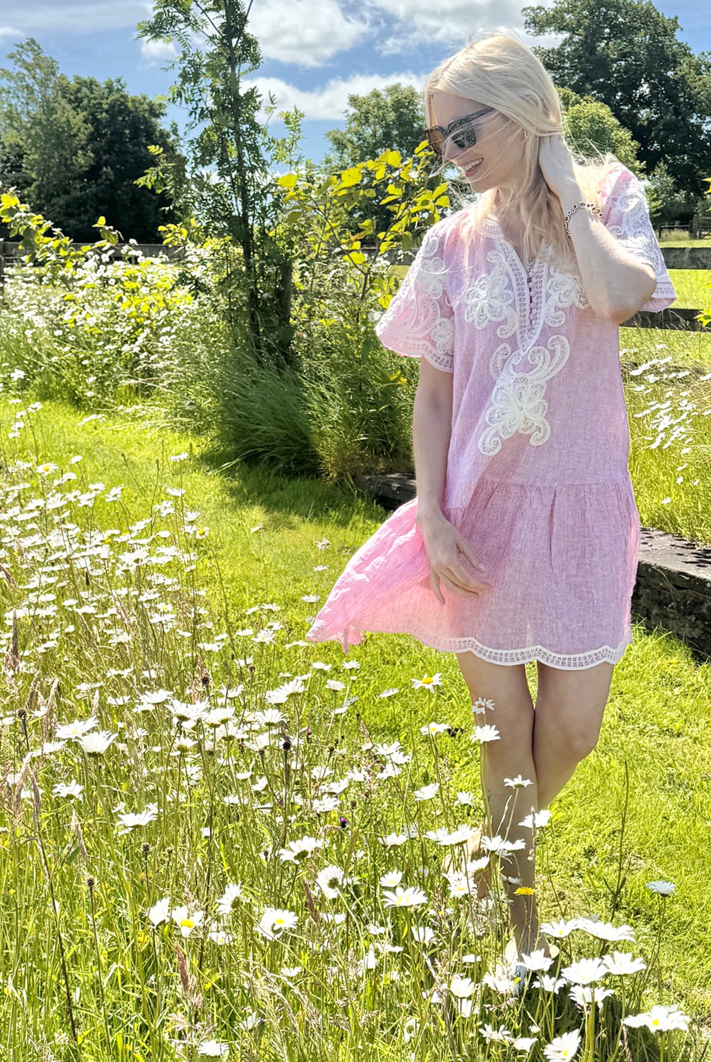Influencer @swedishgirlinlondon wearing the Amaranta red striped dress with white decoration walking in a meadow.
