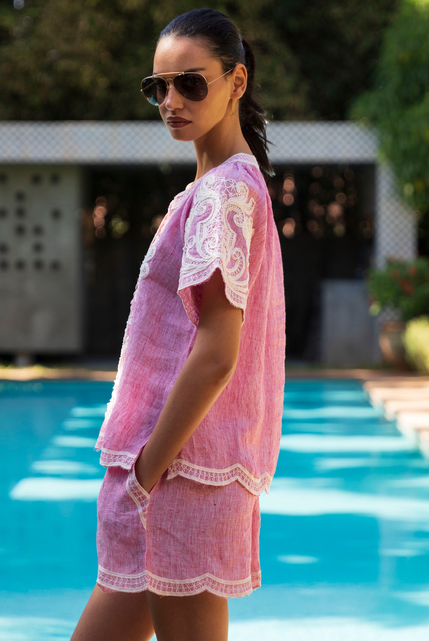 Woman in a red striped Azalea top and matching shorts standing by a pool